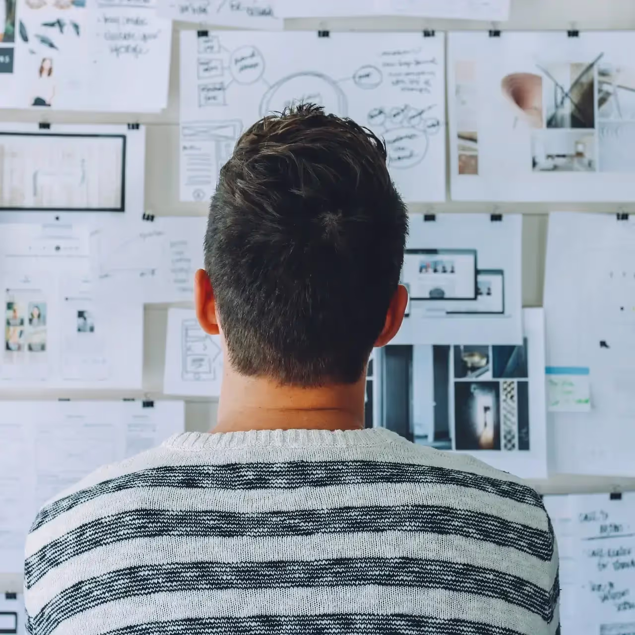 a creative director staring at displayed design work pinned to a wall, waiting to begin a feedback session